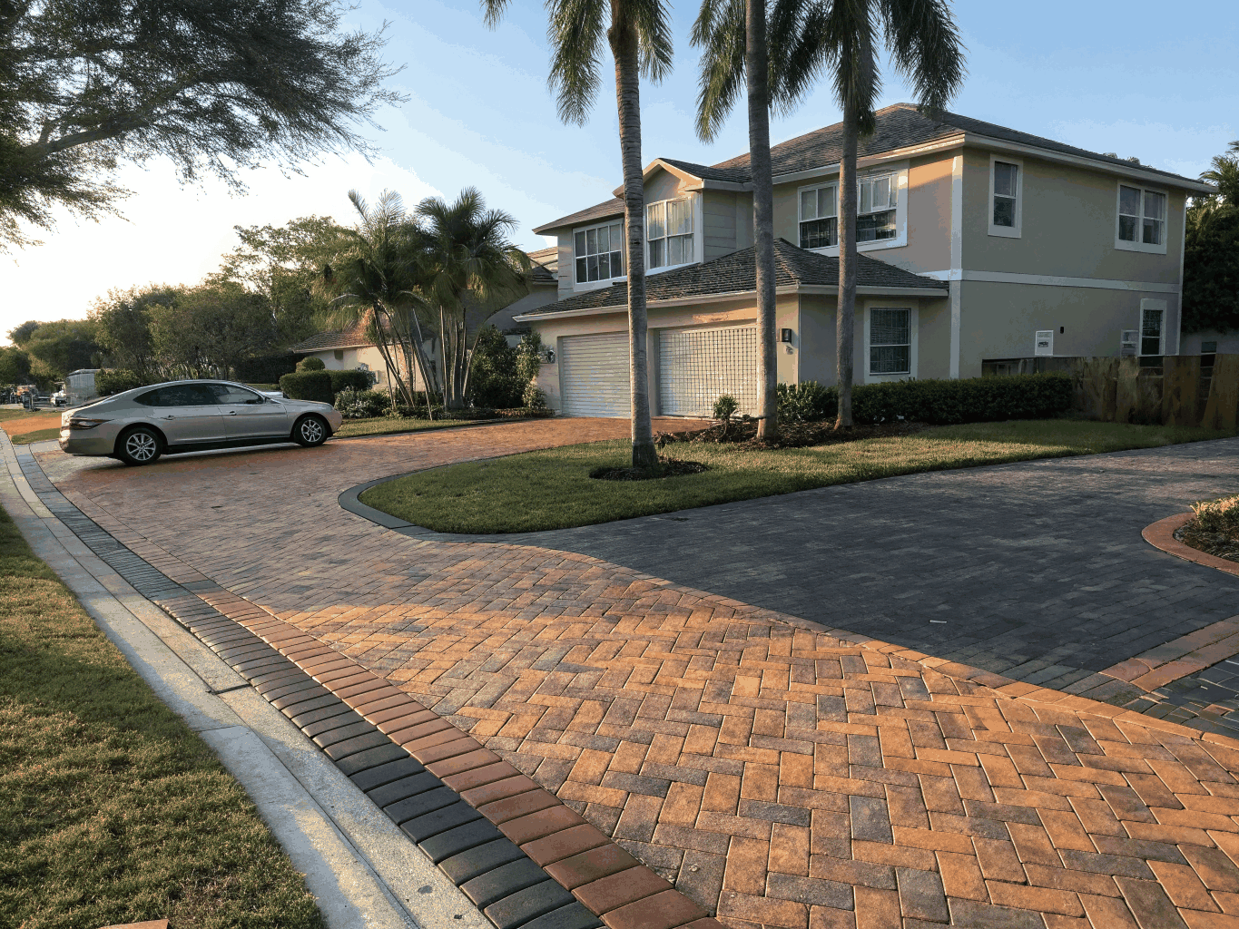 Interlocking herringbone brick paver driveway in warm sunlit earthen tones