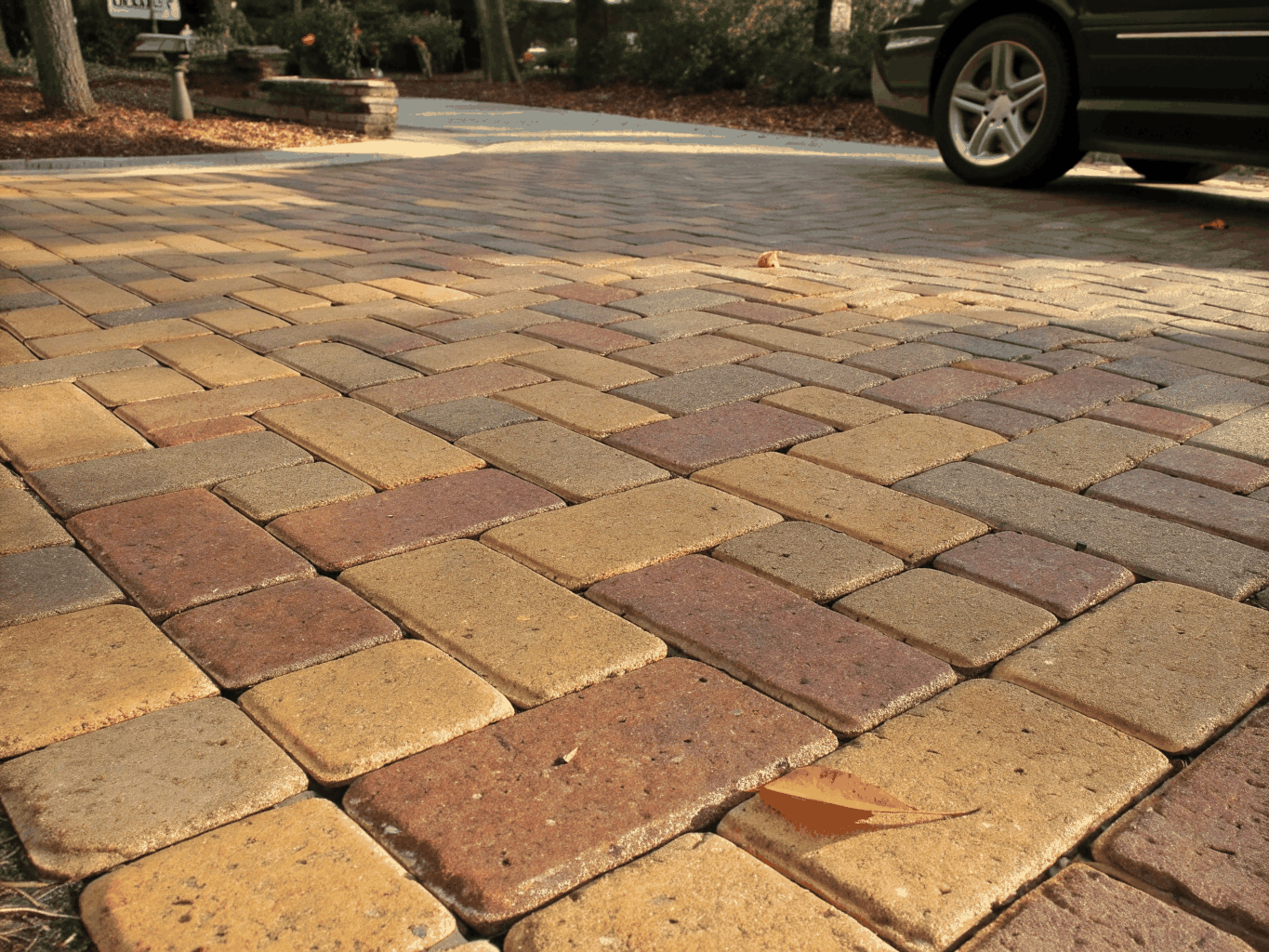 Herringbone pattern brick paver driveway with clean stone border edges