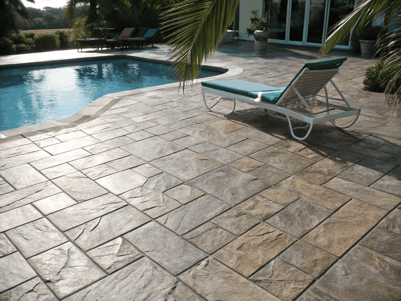 Sunlit stamped concrete pool deck and lounge with smooth bullnose pool coping